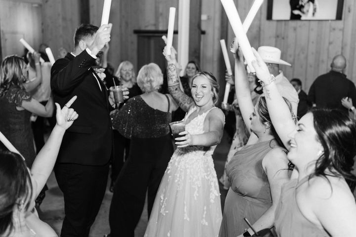 A packed dance floor in black and white, guests waving glow sticks above their heads