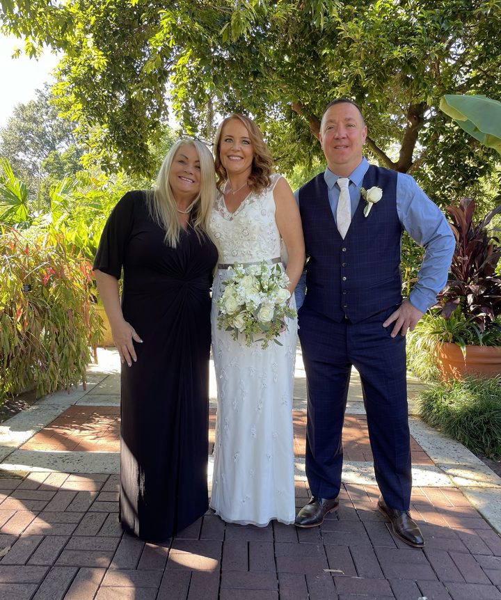 Karin with a bride and groom on a garden path after their ceremony