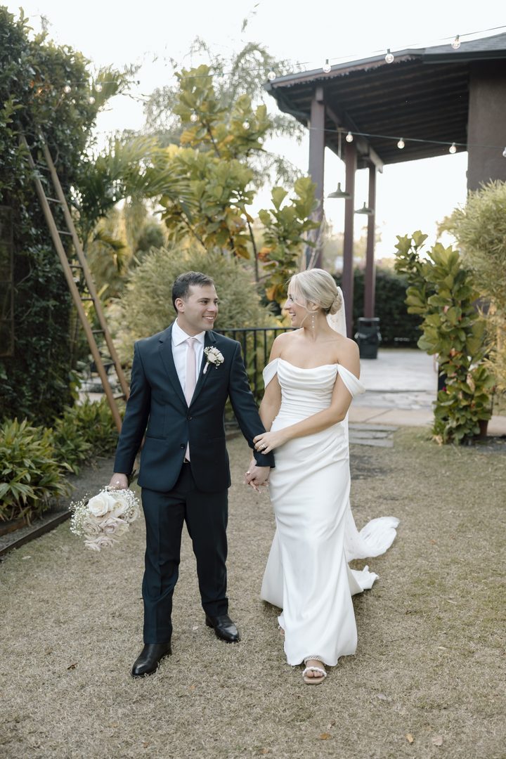 A couple walking hand in hand along a garden path