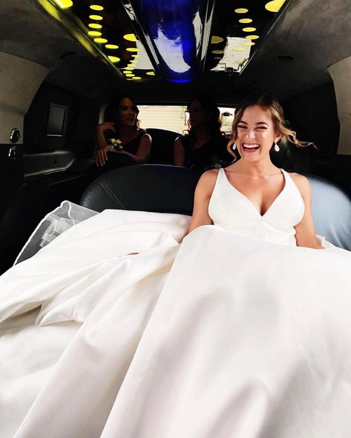 The bride laughing in the back of a limousine with her bridesmaids